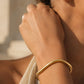 Gold cuff bracelet on their wrist, waterproof jewellery.
