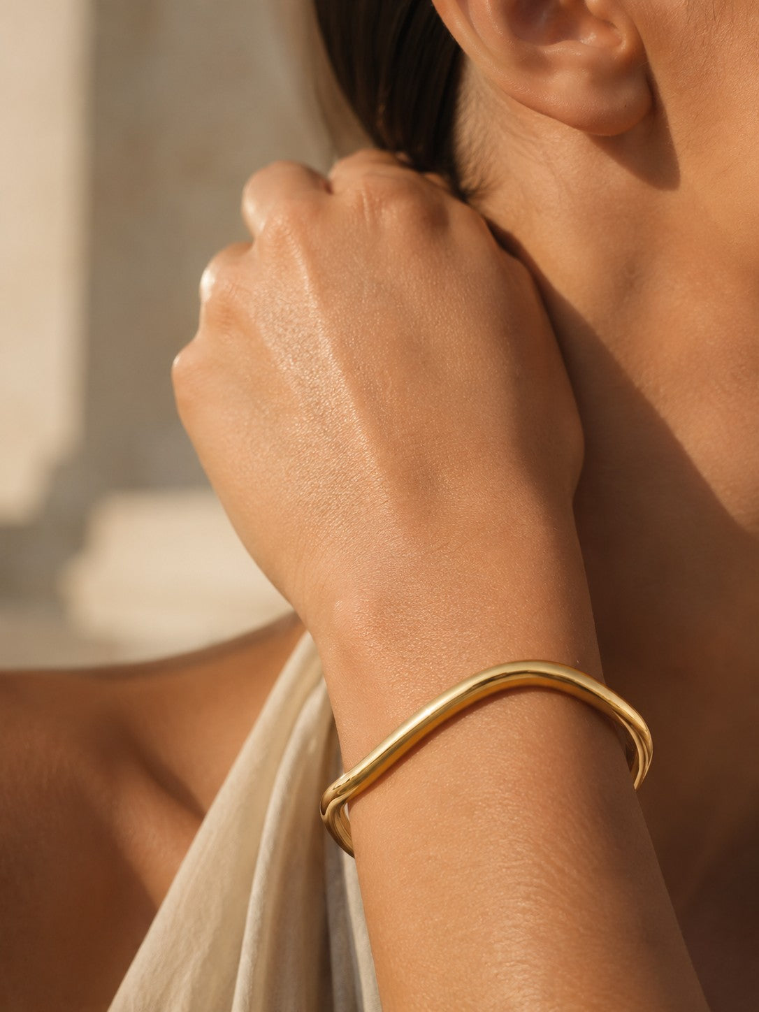 Gold cuff bracelet on their wrist, waterproof jewellery.