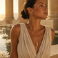Woman wearing a gold quartz crystal pendant necklace beside a tranquil water garden with lotus flowers at golden hour.