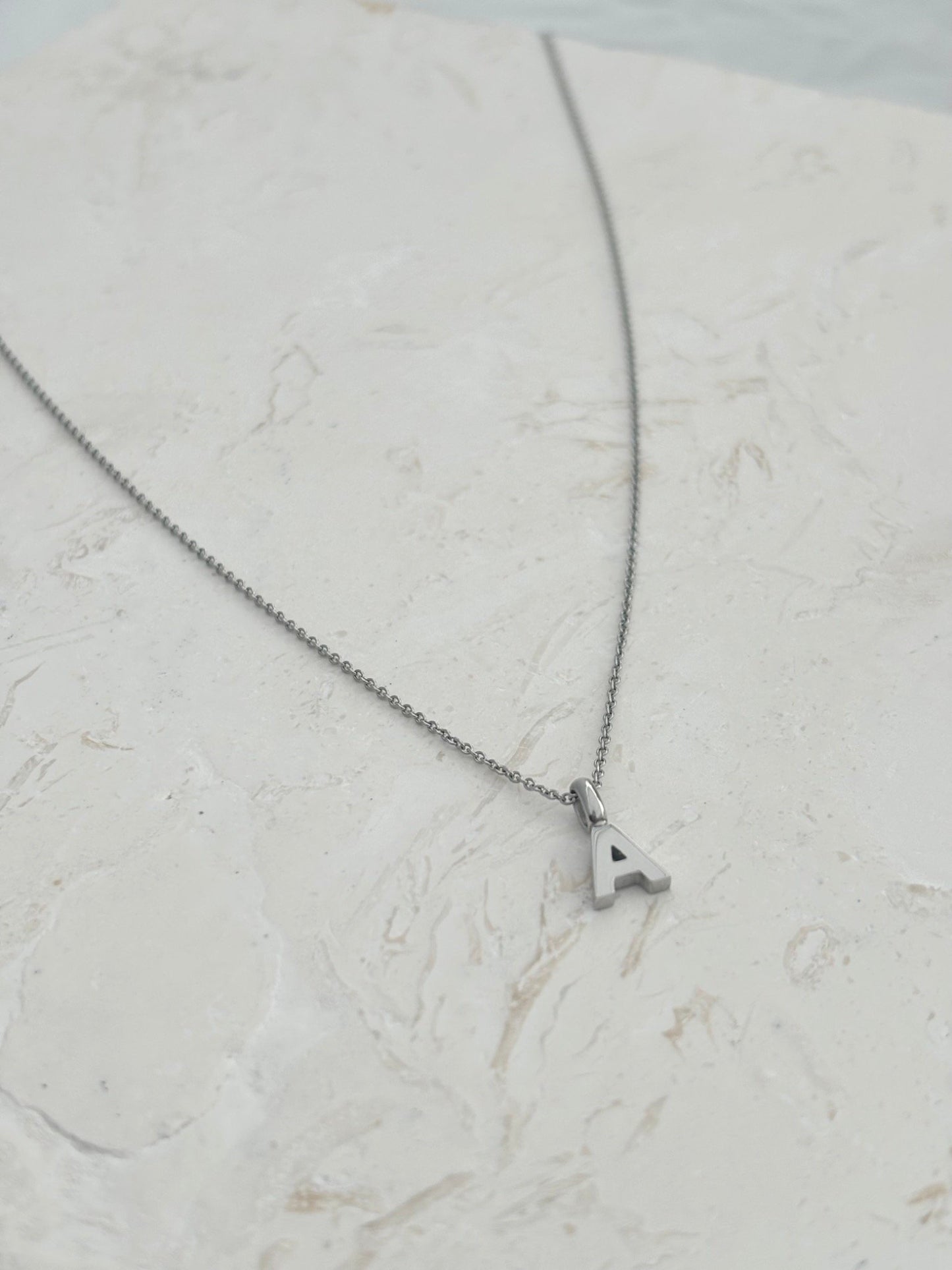 A silver chain necklace with a small letter pendants, that can be personalise. A to Z letters gold and silver
