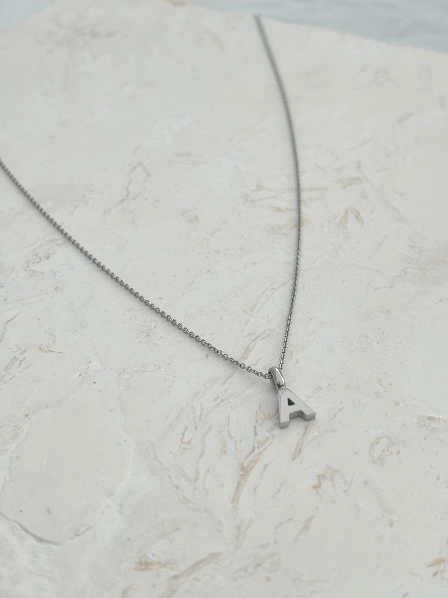 A silver chain necklace with a small letter pendants, that can be personalise. A to Z letters gold and silver