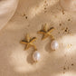 A pair of gold starfish drop earrings with white pearl pendants, styled on a sandy beige surface with soft fabric and a shell.