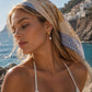 Gold Maris starfish earrings with freshwater pearl drop, worn on a model in warm Mediterranean-inspired styling