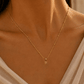Model wearing a gold Letter Charm Necklace as J, R and N initial charms are added one by one.