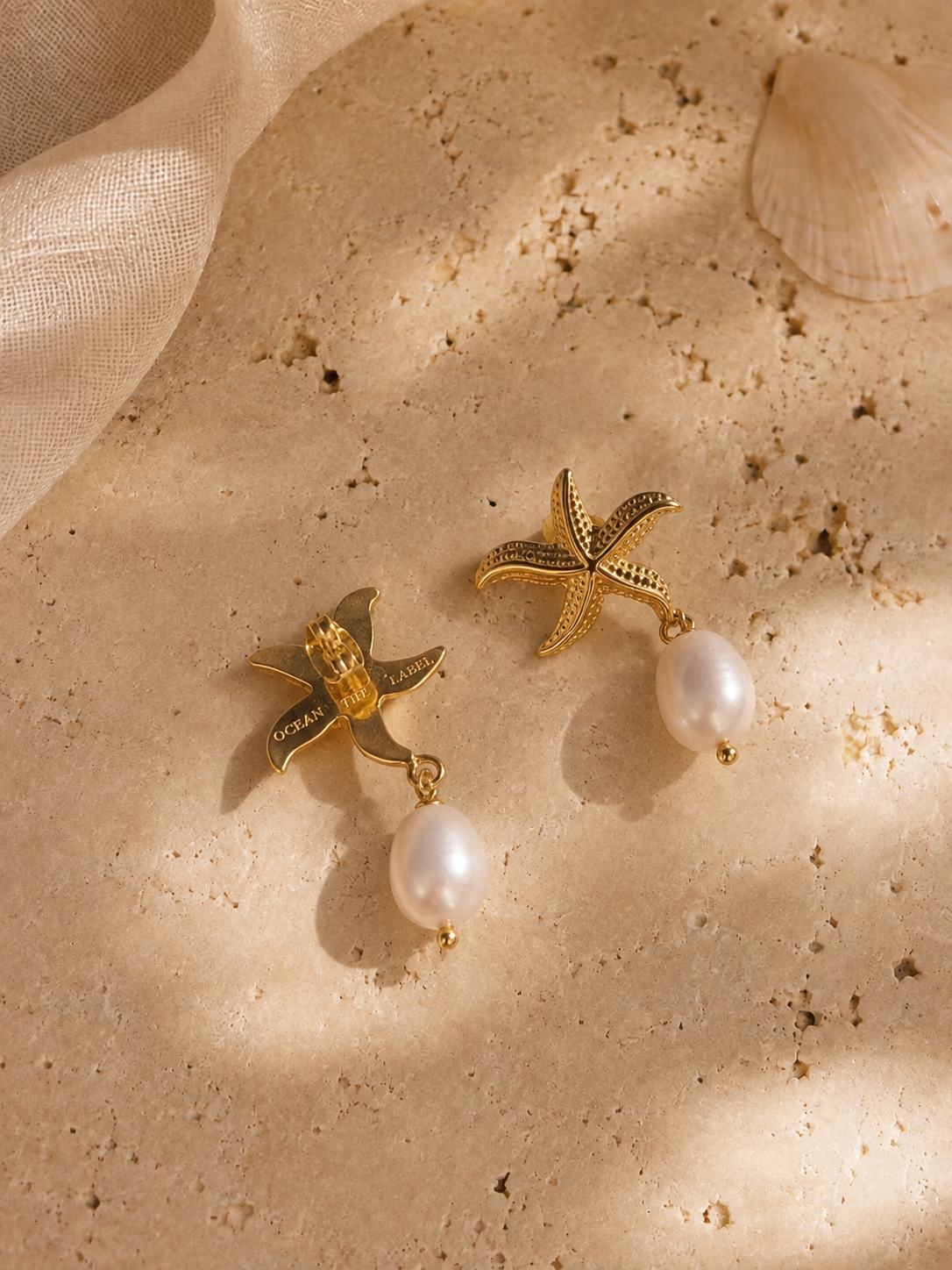Close-up of the Maris gold starfish and pearl earrings worn on the ear, highlighting the intricate gold detailing